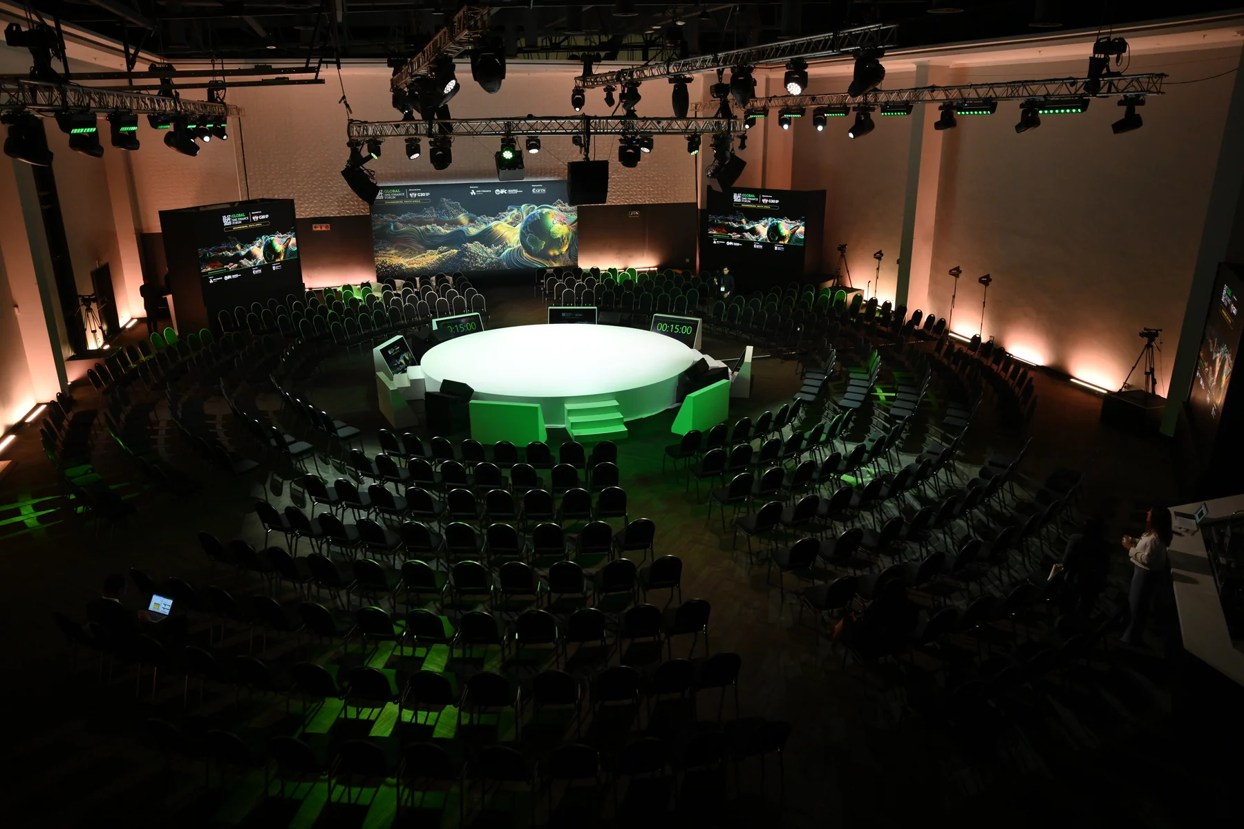 An elevated wide view of Global SME Finance Forum 2025’s circular stage, green fascia and key visual screen